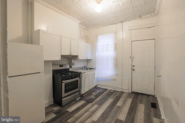 kitchen with white cabinets, stainless steel gas range oven, white refrigerator, and dark hardwood / wood-style flooring