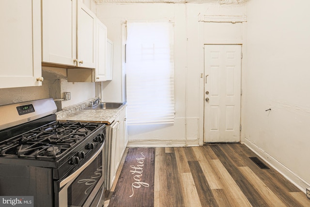 kitchen with white cabinetry, stainless steel gas stove, sink, and dark hardwood / wood-style flooring