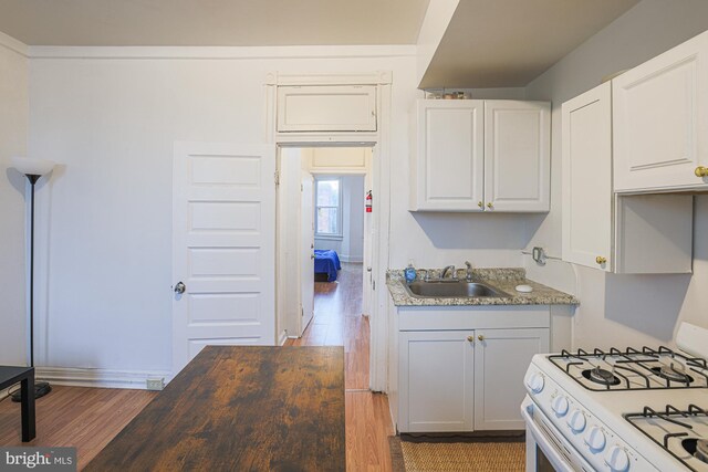 kitchen featuring white cabinets, hardwood / wood-style floors, white range with gas cooktop, and sink