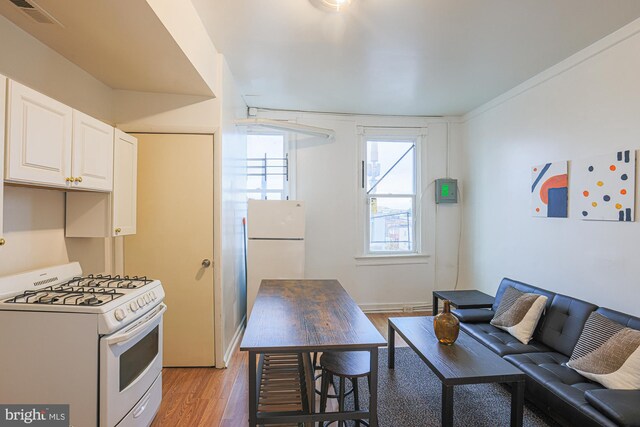 kitchen featuring white cabinets, white appliances, and light wood-type flooring