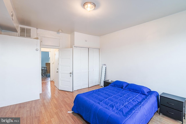 bedroom with light hardwood / wood-style floors and a closet