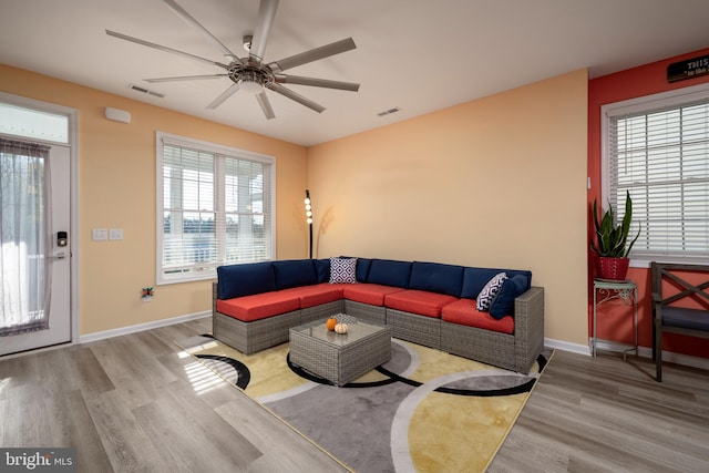 living room with a wealth of natural light, ceiling fan, and light wood-type flooring