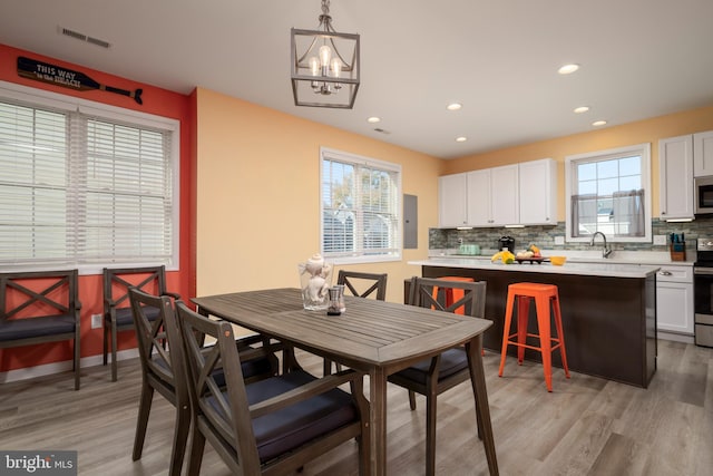 dining area featuring light wood-type flooring, a healthy amount of sunlight, and sink