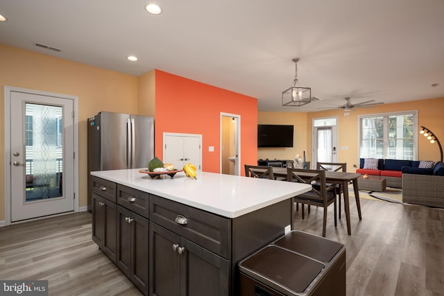 kitchen with pendant lighting, light hardwood / wood-style flooring, ceiling fan, a kitchen island, and stainless steel refrigerator