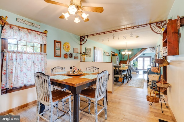 dining room with light hardwood / wood-style floors and ceiling fan with notable chandelier