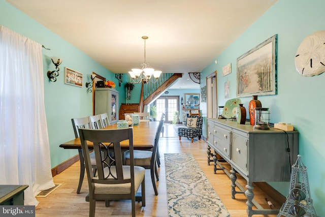 dining space with light hardwood / wood-style flooring and a chandelier