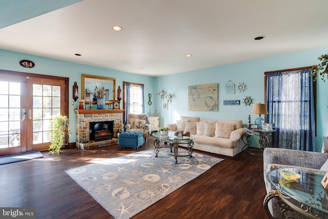 living room featuring dark wood-type flooring, french doors, a healthy amount of sunlight, and a fireplace