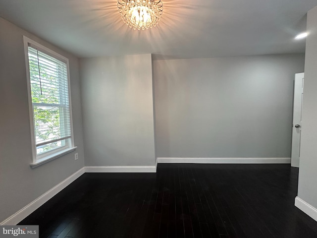 unfurnished room with dark wood-type flooring and a chandelier