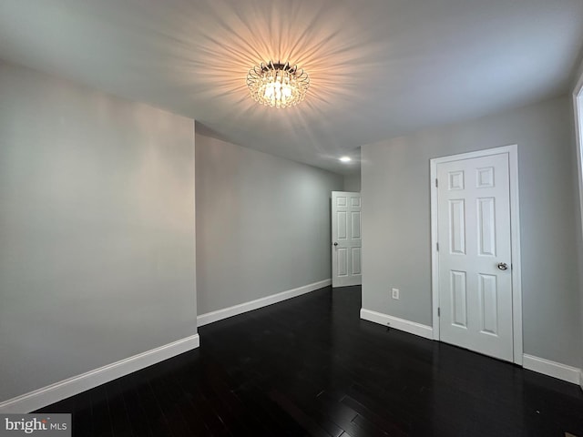 empty room featuring a notable chandelier and dark hardwood / wood-style floors