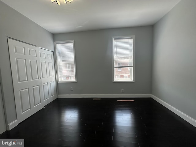 unfurnished bedroom featuring a closet and dark hardwood / wood-style flooring