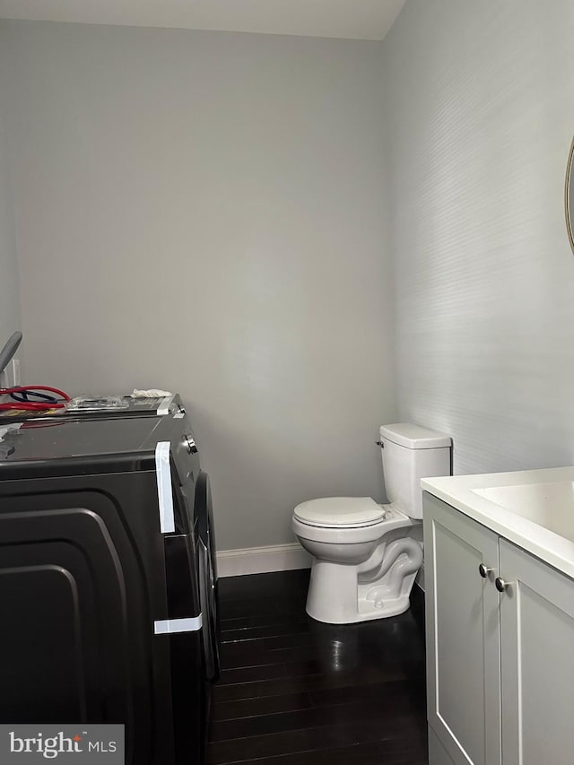 bathroom featuring washer and clothes dryer, vanity, hardwood / wood-style floors, and toilet