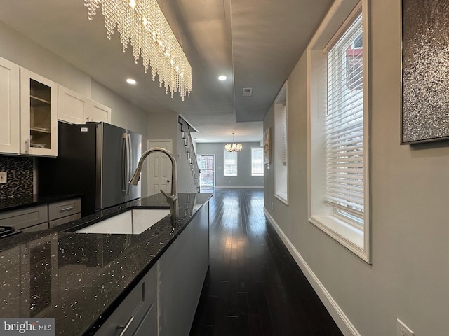 kitchen with white cabinetry, dark hardwood / wood-style floors, dark stone countertops, a notable chandelier, and pendant lighting