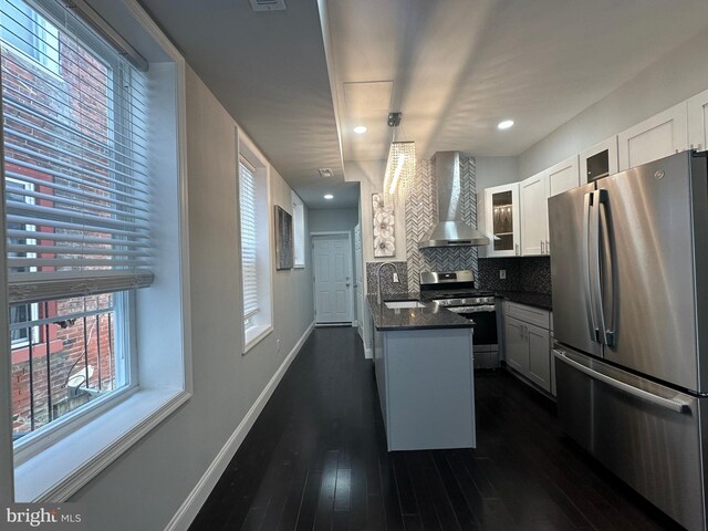 kitchen featuring stainless steel appliances, wall chimney exhaust hood, white cabinetry, and sink