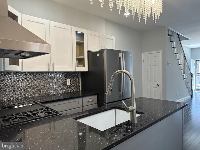 kitchen featuring dark stone countertops, wall chimney exhaust hood, wood-type flooring, white cabinets, and stainless steel fridge