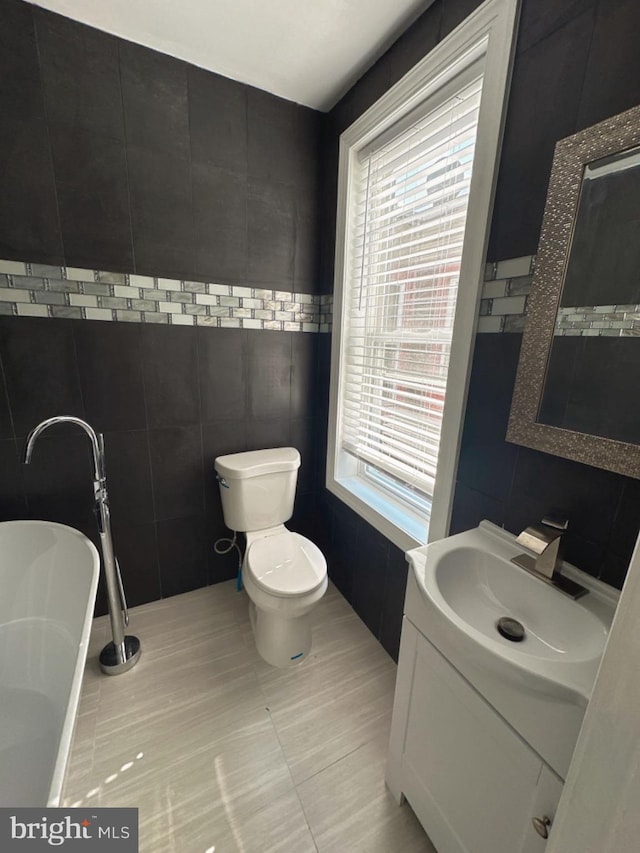 bathroom featuring tile walls, a wealth of natural light, vanity, and a bath