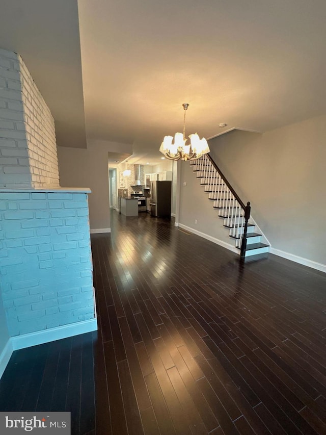 unfurnished living room featuring dark hardwood / wood-style flooring and a chandelier