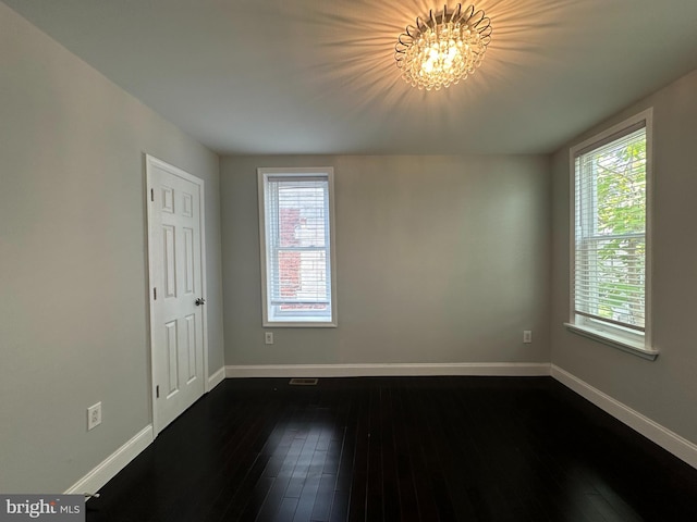 unfurnished room featuring dark hardwood / wood-style flooring and an inviting chandelier