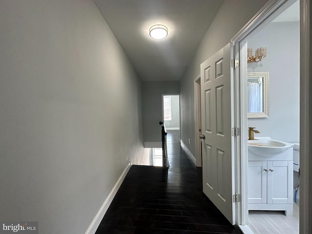 hall with dark wood-type flooring, sink, and lofted ceiling