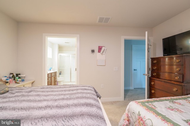 bedroom featuring ensuite bath and light colored carpet