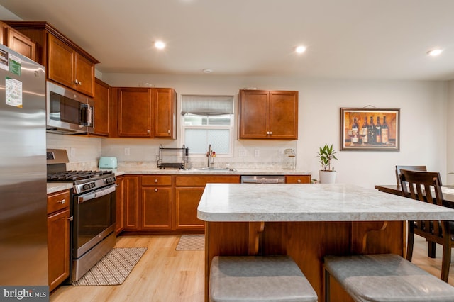 kitchen featuring a kitchen breakfast bar, light hardwood / wood-style floors, sink, and stainless steel appliances