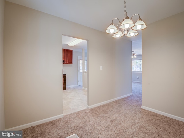 empty room with a wealth of natural light, light carpet, and ceiling fan with notable chandelier