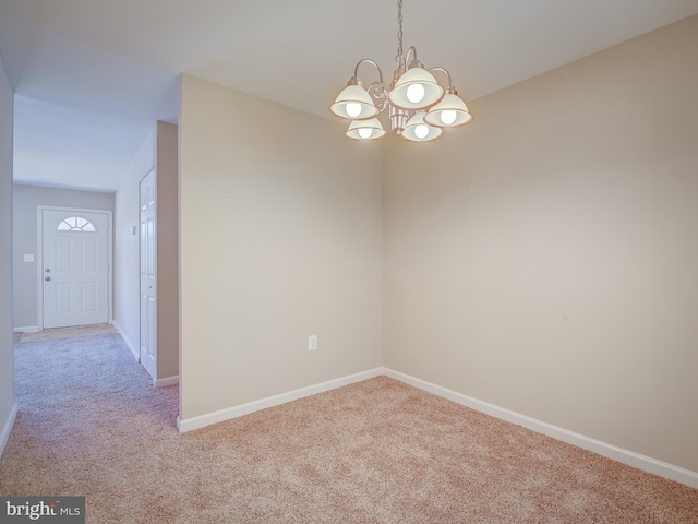 carpeted spare room featuring an inviting chandelier