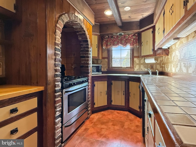 kitchen with sink, wooden ceiling, beam ceiling, backsplash, and appliances with stainless steel finishes