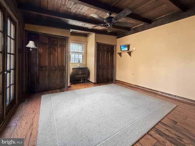 unfurnished bedroom featuring ceiling fan, hardwood / wood-style flooring, beamed ceiling, and wood ceiling