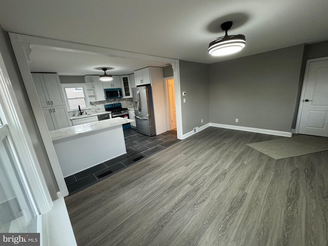 kitchen featuring sink, dark hardwood / wood-style floors, backsplash, white cabinets, and appliances with stainless steel finishes