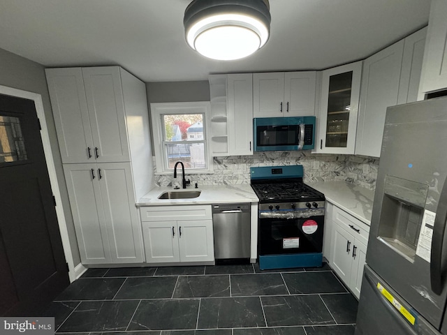 kitchen featuring decorative backsplash, stainless steel appliances, dark tile patterned floors, sink, and white cabinets