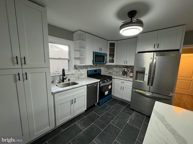 kitchen featuring decorative backsplash, light stone counters, sink, black appliances, and white cabinets