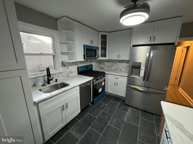 kitchen featuring appliances with stainless steel finishes, backsplash, white cabinetry, and sink