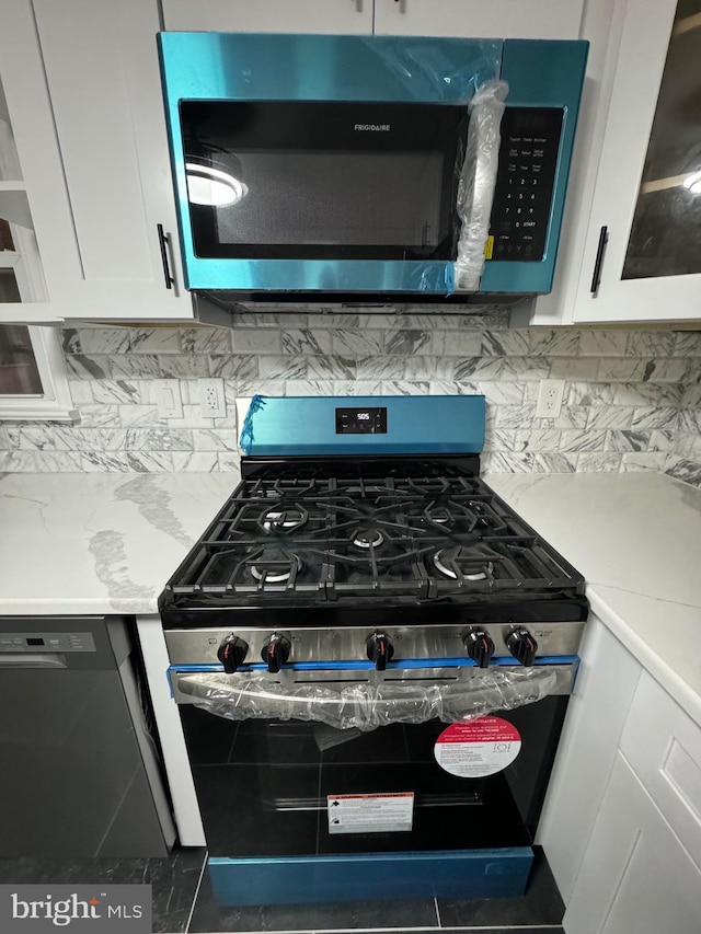 details with tasteful backsplash, white cabinets, and appliances with stainless steel finishes