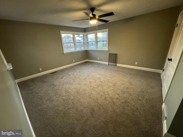 unfurnished bedroom featuring ceiling fan, dark carpet, and a textured ceiling