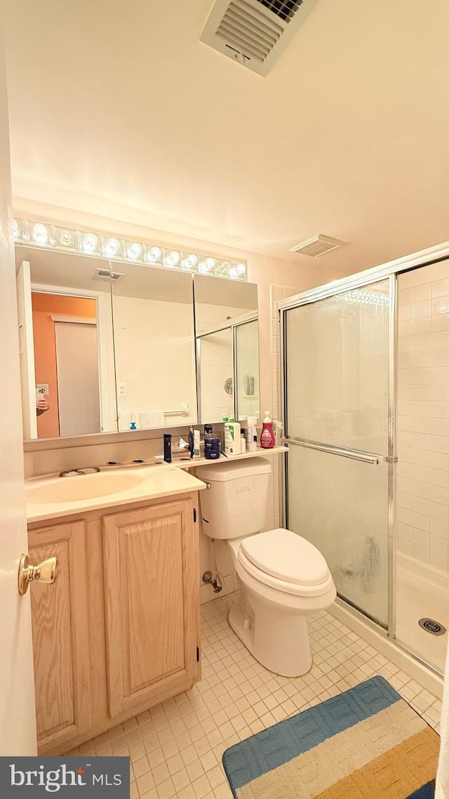 bathroom with vanity, tile patterned flooring, toilet, and an enclosed shower