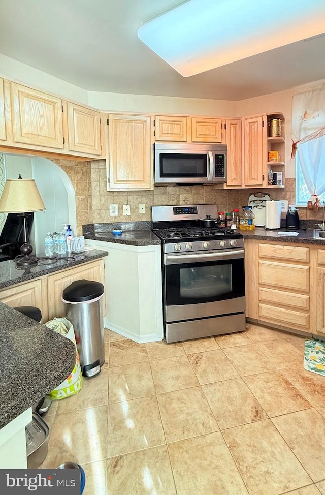 kitchen with light brown cabinetry, decorative backsplash, light tile patterned floors, and stainless steel appliances