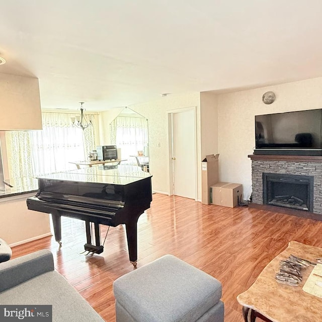 misc room featuring light hardwood / wood-style floors, a stone fireplace, and a chandelier