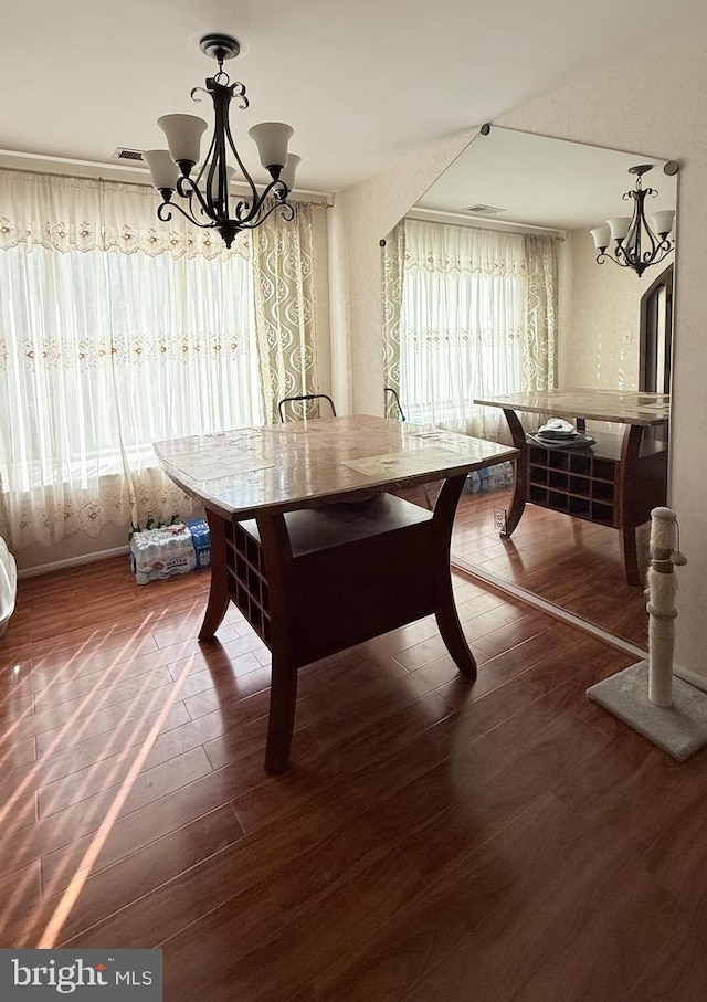 dining space with dark wood-type flooring and a notable chandelier