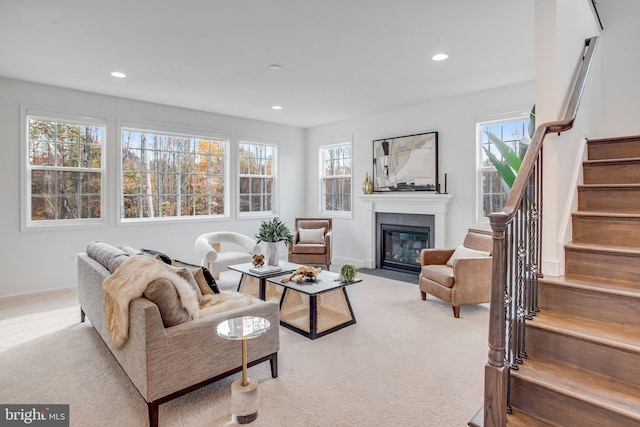 living room featuring carpet floors, stairway, a fireplace with flush hearth, plenty of natural light, and recessed lighting