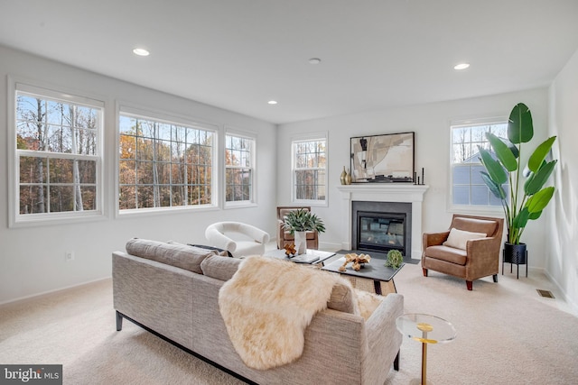 living area featuring carpet flooring, a glass covered fireplace, baseboards, and recessed lighting