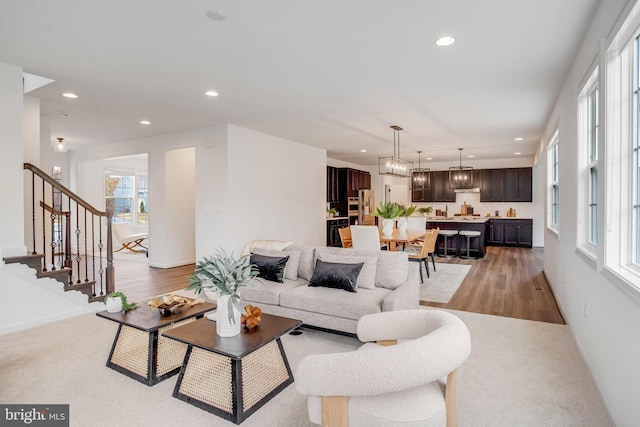 living room with recessed lighting, stairs, light wood-type flooring, baseboards, and light colored carpet