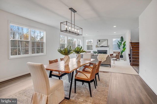 dining area with recessed lighting, wood finished floors, baseboards, a fireplace, and a chandelier