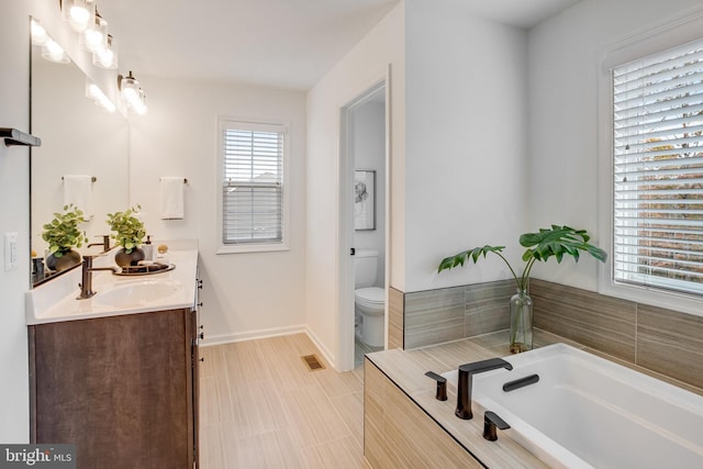 full bath with toilet, baseboards, a garden tub, and double vanity