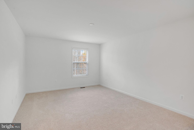 unfurnished room with light carpet and baseboards