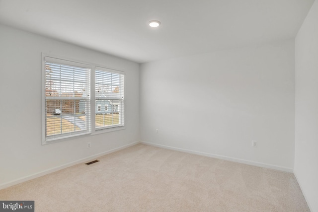 empty room featuring light colored carpet and baseboards