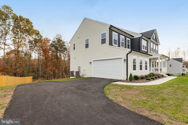 view of property exterior featuring central AC, a garage, a yard, and a porch