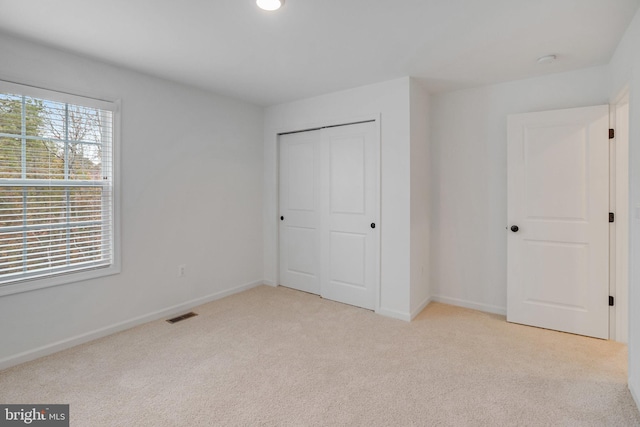 unfurnished bedroom featuring light colored carpet and a closet