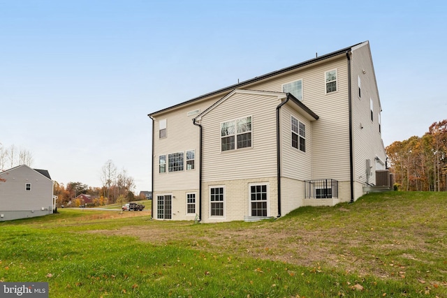 rear view of house with central AC and a yard