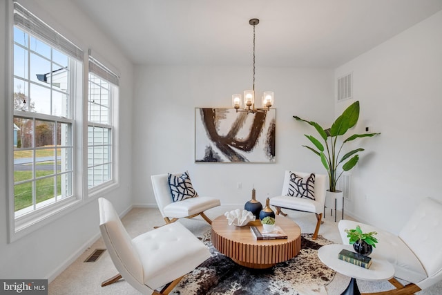 living area featuring carpet flooring, baseboards, and a chandelier