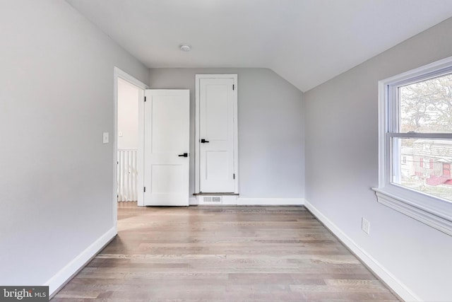 additional living space with light wood-type flooring and lofted ceiling